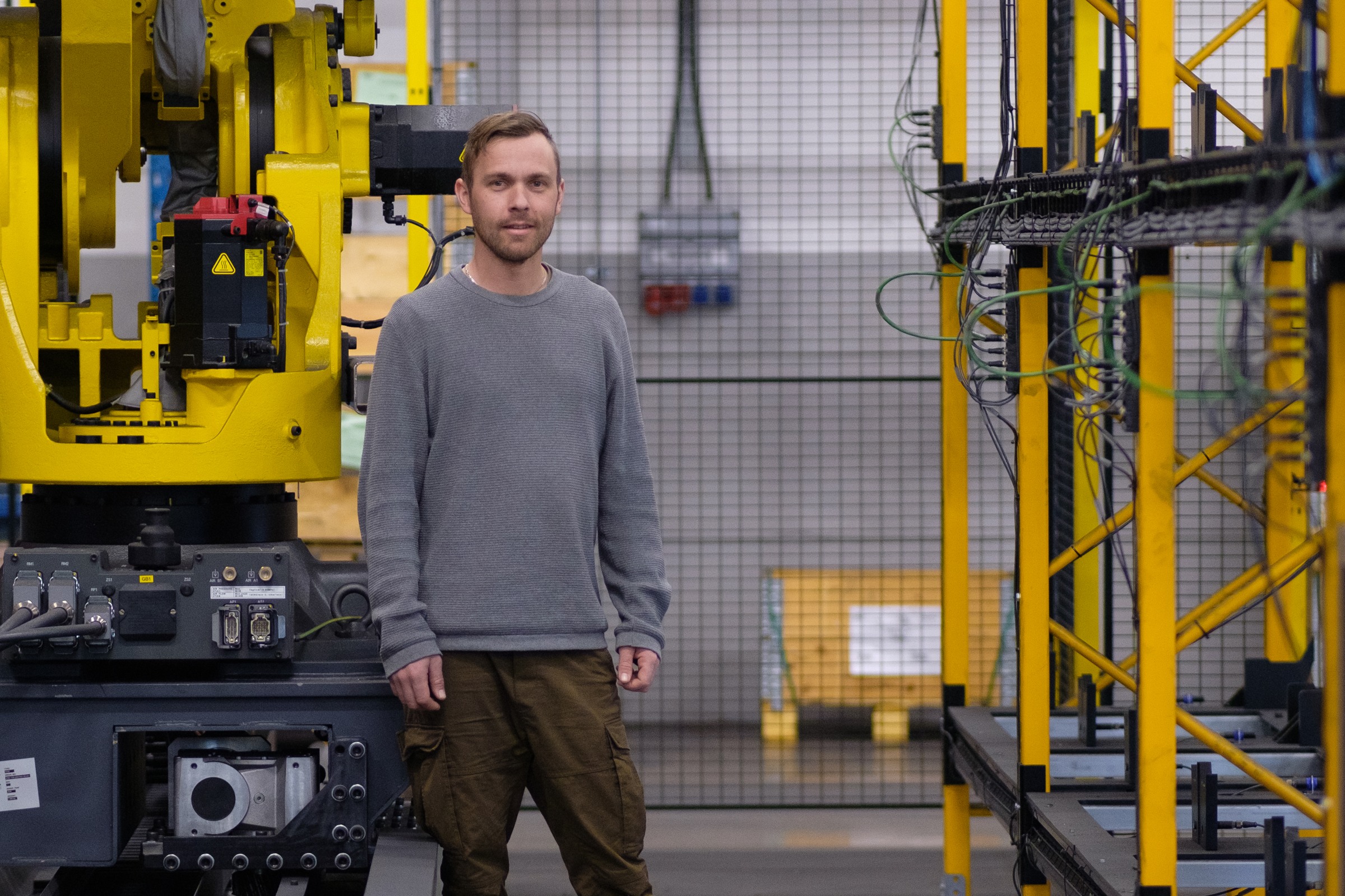 Projektledare Alexander Harbrecht i en industrilokal med gula maskiner.